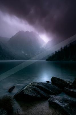 A night long exposure sky scene of storm, lake, mountains.