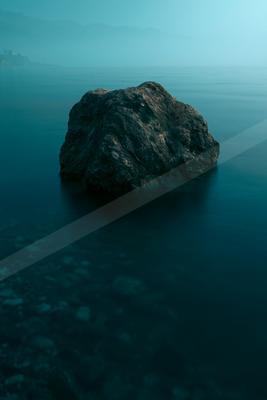 A blue hour high contrast water scene of an ocean, rocks.