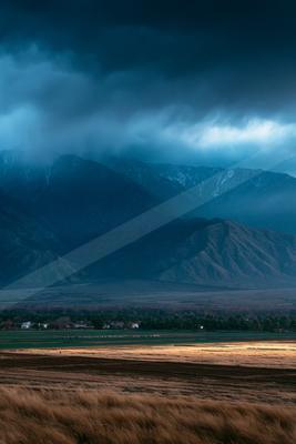 A moody landscape of mountains, valley, storm.