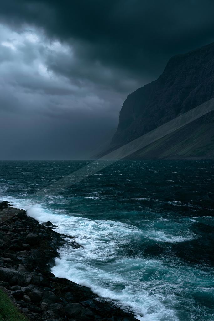 A black-toned moody photograph of seashore, cliff, promontory.