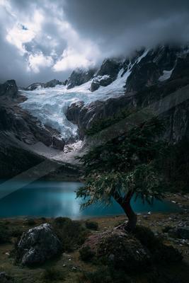 A serene landscape of mountains, trees, lake.