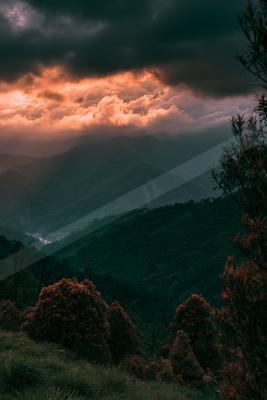 A dramatic landscape of mountains, clouds, valley.