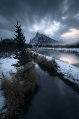 A moody landscape of mountains, lake, valley.
