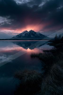 A blue hour water scene of lake, mountains, reflection.