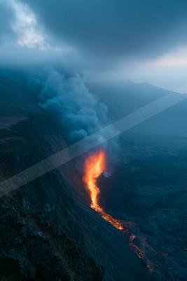 A black-toned moody photograph of volcano, geyser, cliff.