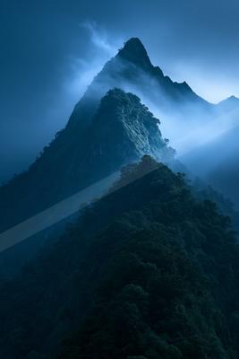 A blue hour high-key landscape of a mountains, fog.