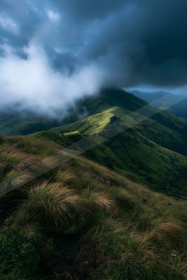 A moody landscape of mountains, field, valley.