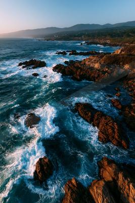 A moody water scene of ocean, waterfall, beach.
