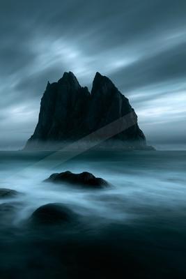 A blue hour long exposure landscape of mountains, ocean, fog.
