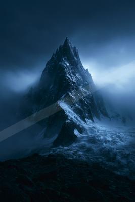 A dramatic landscape of mountains, fog.