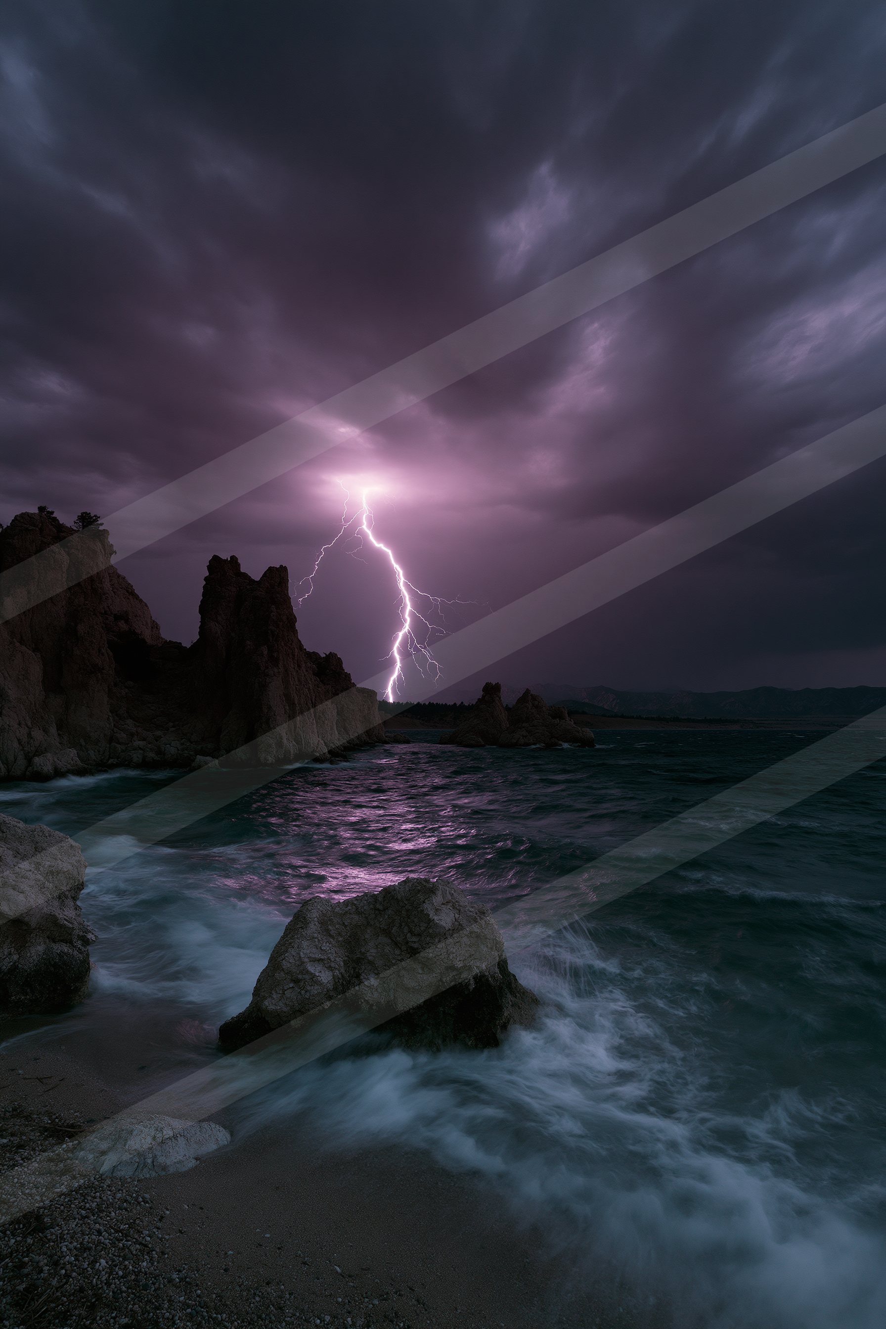 A powerful lightning bolt illuminates the dark sky over a rocky shoreline during a storm.