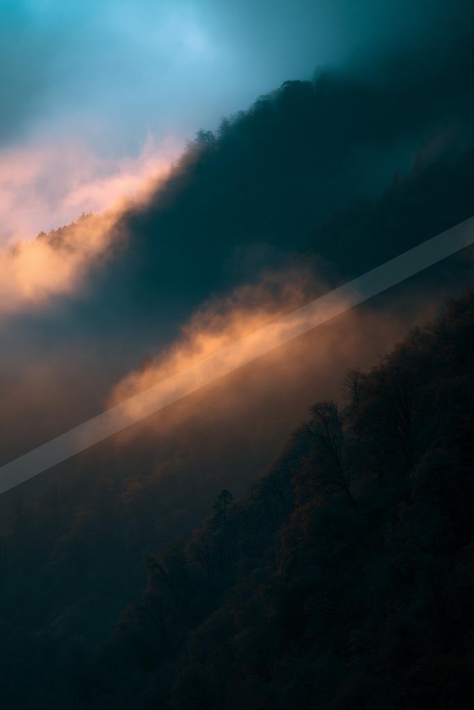 A blue hour sky scene of clouds, sunrise, mountains.