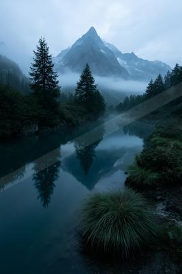 A serene landscape of mountains, lake, valley.